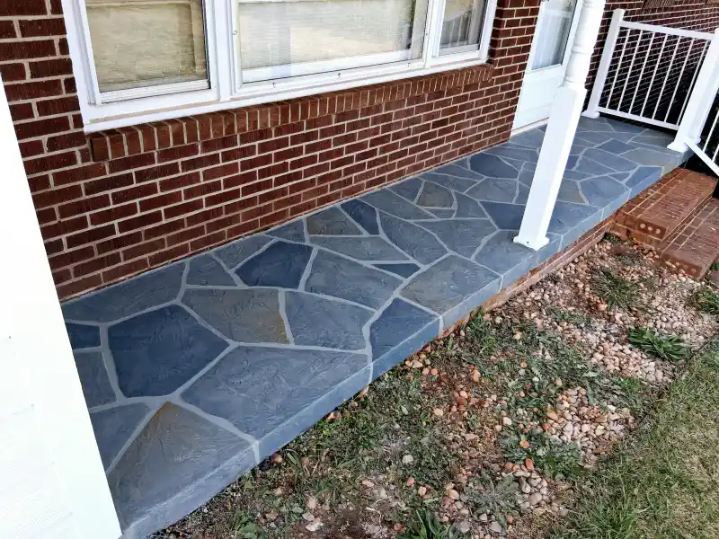 A blue-grey flagstone-pattern overlay applied to a narrow porch slab and its step edge against a red brick house.