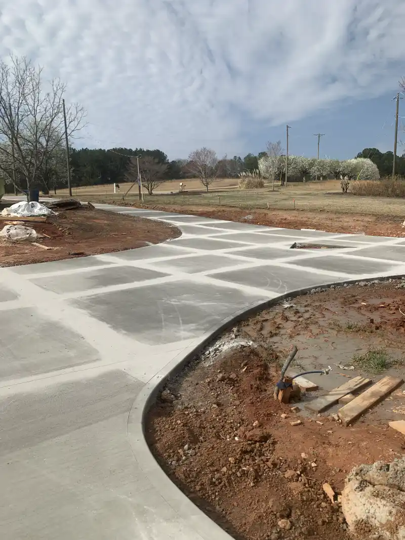 A concrete driveway widening into a vehicle turnaround pad.