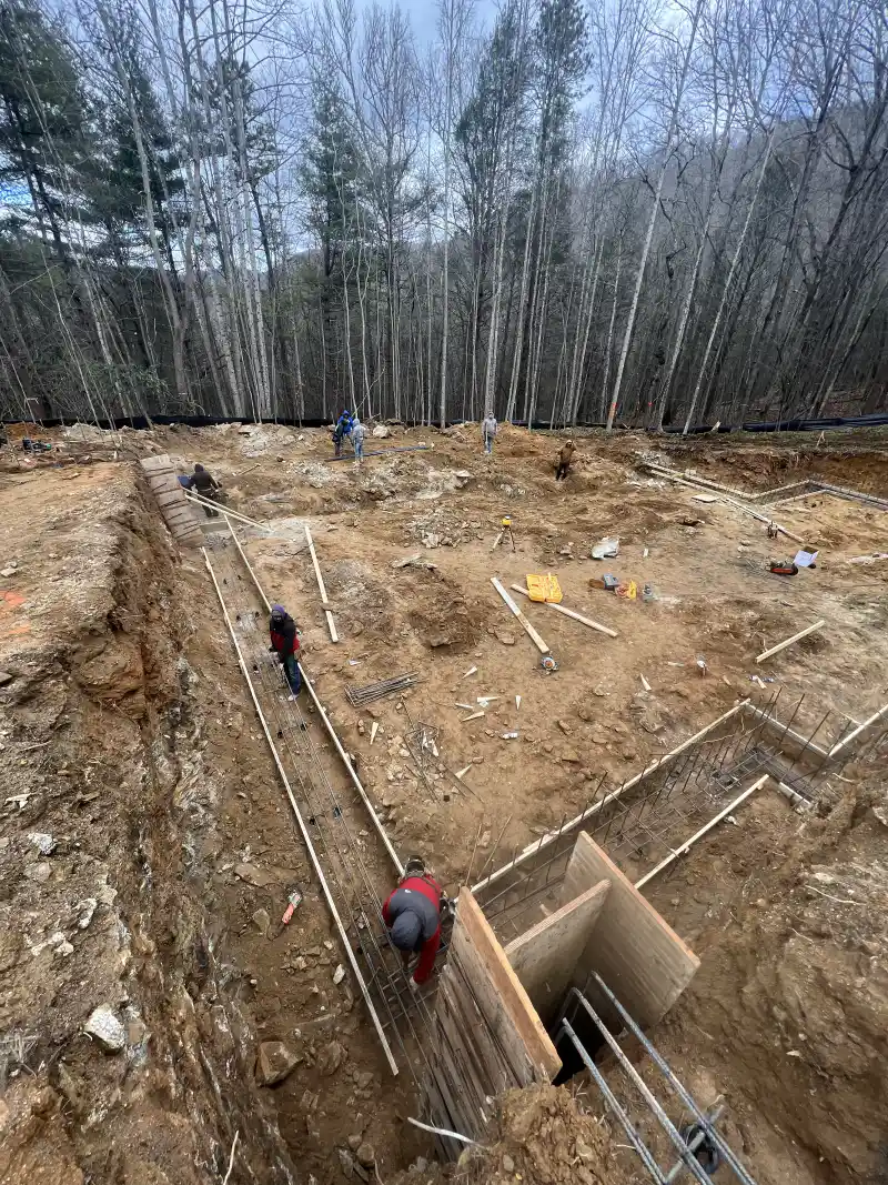 A deep footing excavation with tied steel reinforcing cages in place and workers on site.