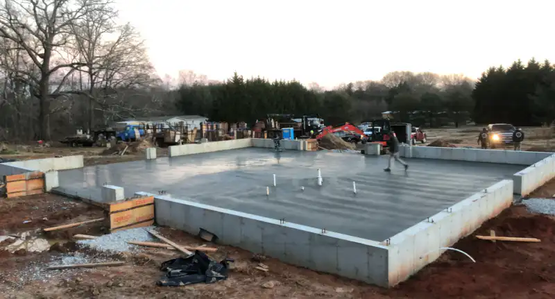 A foundation work site photographed at dusk with crew and vehicles in the background.