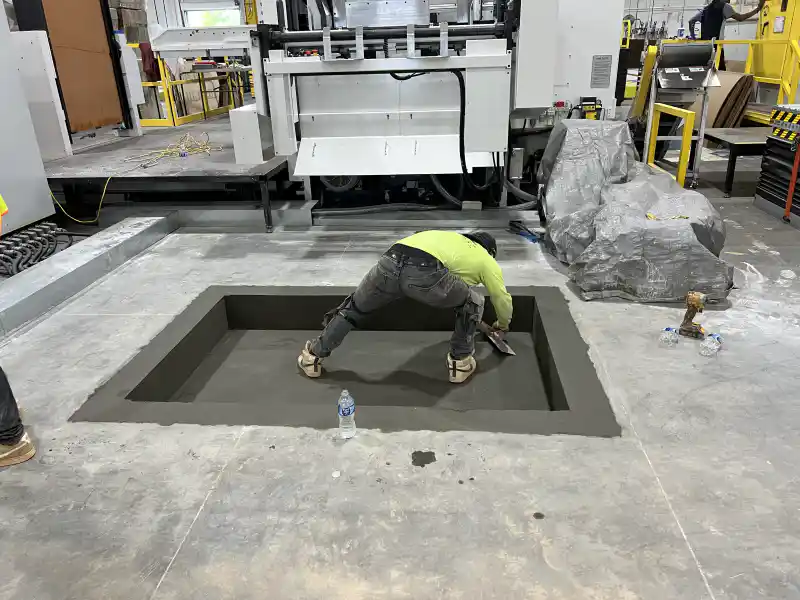 A concrete machine base poured inside a manufacturing plant interior.