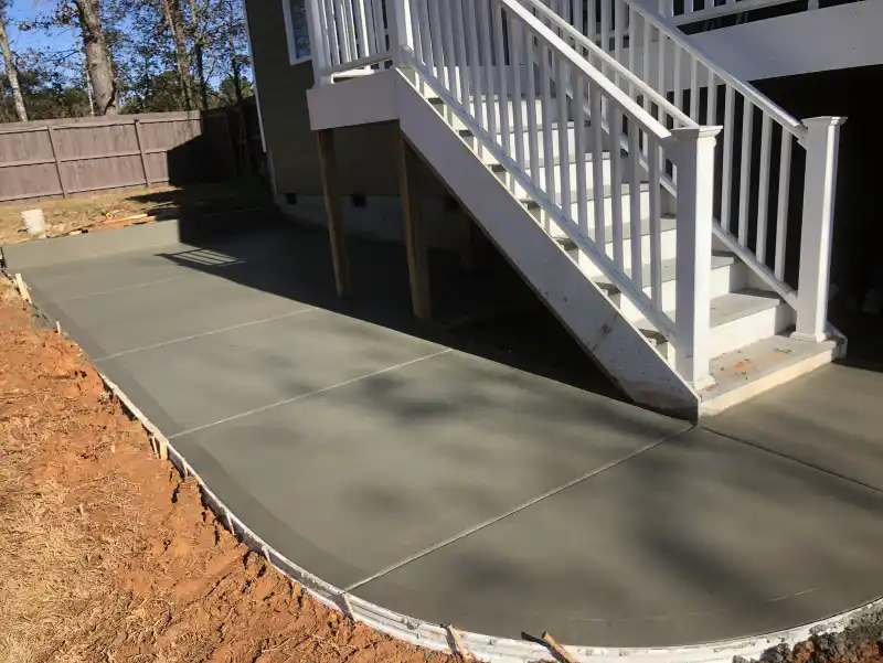 A concrete patio beneath a covered roof structure supported on posts.