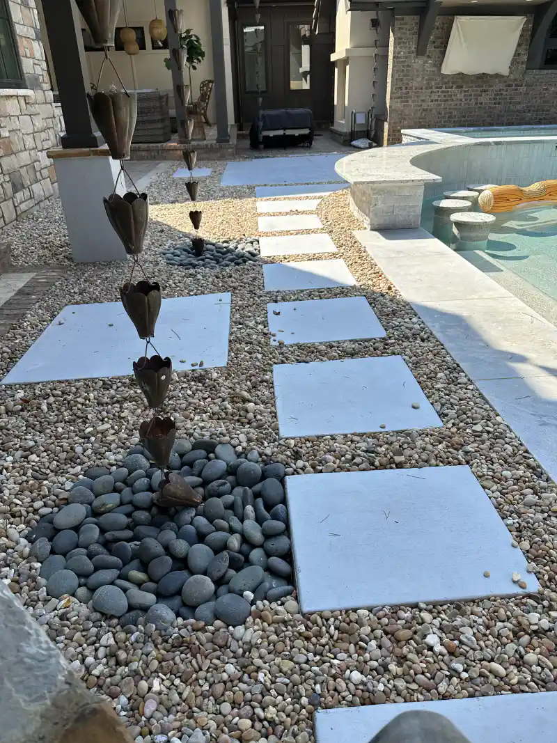 Square concrete pads set into gravel alongside a swimming pool.