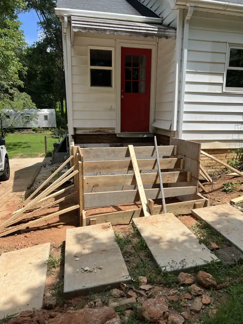 Worn existing steps at a house entrance before replacement.