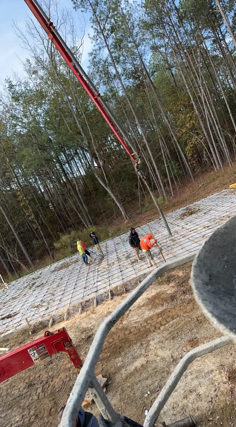 Workers placing concrete for a building slab while a boom pump delivers the pour.
