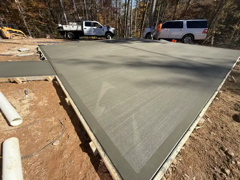 A finished concrete slab with a broom-finished border band, photographed against autumn foliage.
